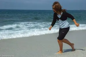 Jente leker i strand av kvarts med blått hav