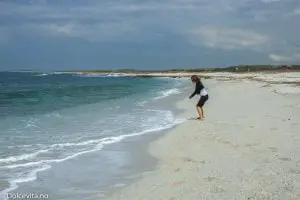 Jente leker i strand av kvarts med blått hav